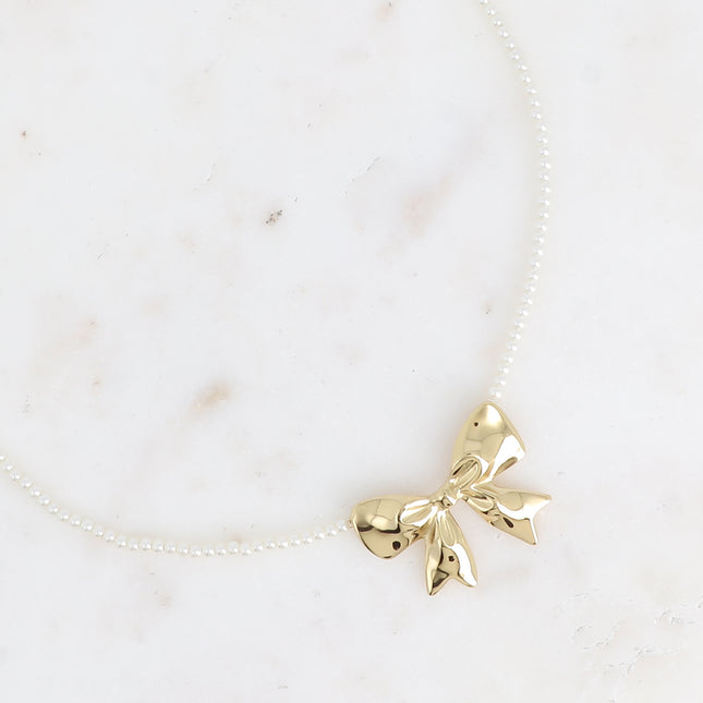 Collier sur câble Zénaïe - ras de cou, perles de résine blanche et pendentif noeud papillon