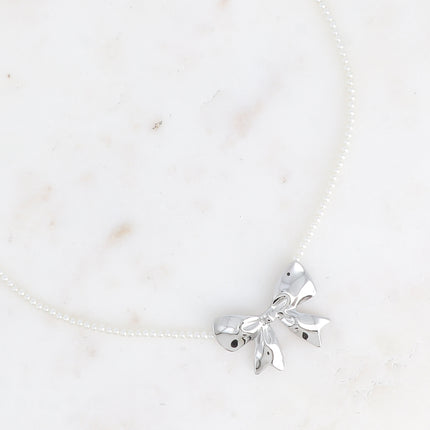 Collier sur câble Zénaïe - ras de cou, perles de résine blanche et pendentif noeud papillon